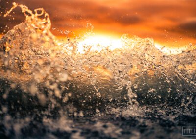 time frozen crashing wave backlit by sunrise